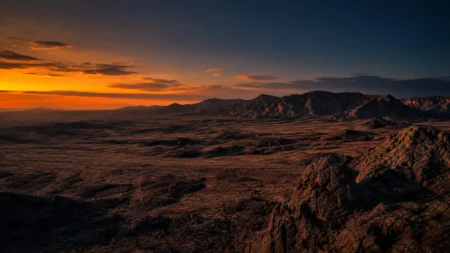 オレンジと紺のグラデーションに染まる荒野の夕景、岩山のシルエット
