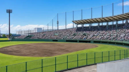 満員のスタンドが見える高校野球のスタジアム、昼間の強い日差しの中のグラウンド