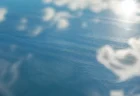 強い日差しの下で雲と青空を反射するガラス面