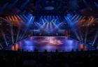 夜のアリーナ会場でカラフルなスポットライトが交錯するダンスステージと観客シルエット