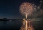 夜の湖畔に打ち上がる花火と湖面の反射