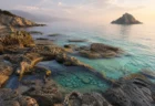 夕方の柔らかい光に照らされた、人魚伝説を思わせる島の海岸風景