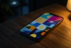 夜の部屋で木製デスクに置かれたスマートフォン、画面にはカラフルな漫画パネル風のイラストが表示されている
