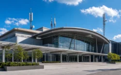 青空の下、大型展示場の外観と通信用アンテナ