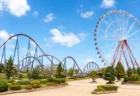 青空の下に観覧車とジェットコースターが並ぶ遊園地の情景