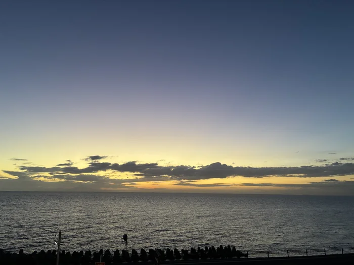 画像 日没後、水平線がオレンジに染まる海と空