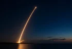 夜明け前の海沿いの発射場から打ち上げられるロケットの光跡のイメージ