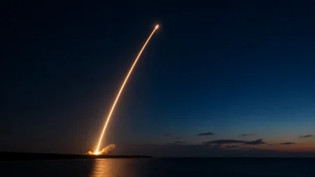 夜明け前の海沿いの発射場から打ち上げられるロケットの光跡のイメージ