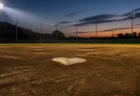 夕方のナイター照明に照らされた高校野球のグラウンドとベース