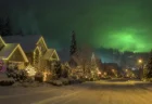 クリスマスイルミネーションが輝く雪の積もった住宅街の夜景、緑色の光に覆われた空の幻想的情景