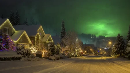 クリスマスイルミネーションが輝く雪の積もった住宅街の夜景、緑色の光に覆われた空の幻想的情景
