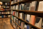 温かい照明の書店で本が斜めに並ぶ棚の情景