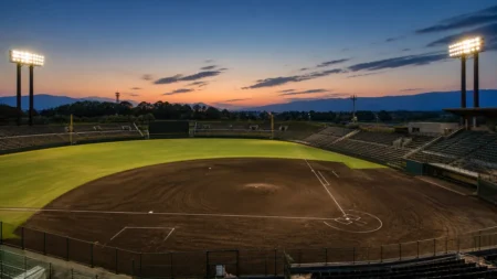 夕暮れの野球場、ナイター照明が灯り始めた無人のグラウンド全景