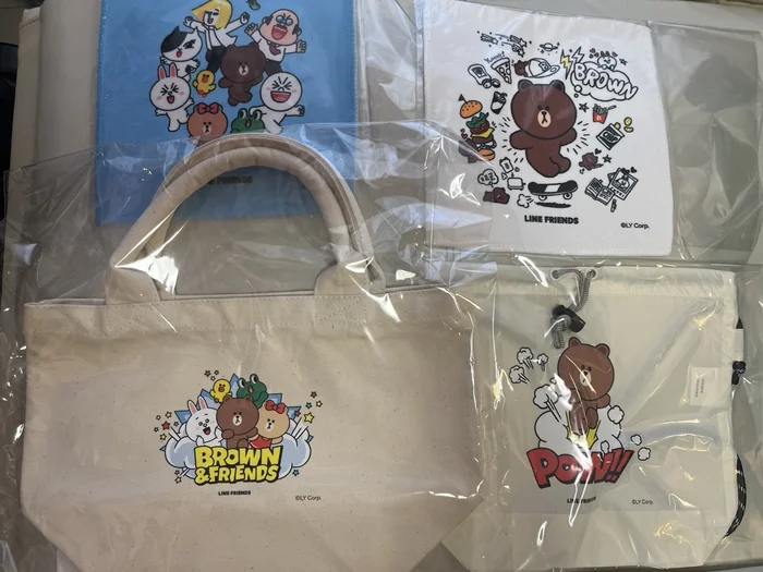 LINE FRIENDS ART展の会場限定グッズ。キャラクターが描かれたハンドタオル、BROWN & FRIENDSのトートバッグ、POW!!のサコッシュ