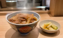 湯気の立つ牛めしとサイドメニューが並ぶ和食チェーン店のカウンター席のイメージ