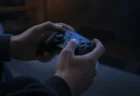 テレビの光を受けてゲームコントローラーを操作する手元