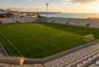 夕暮れの海沿いの町にある無人のサッカースタジアム