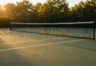 夕方の光が差し込む無人のテニスコートとネット