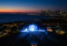 夏の野外音楽フェスのメインステージを俯瞰した夕暮れの情景、ステージ照明とスモーク演出
