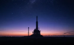 夜明け前の発射場に立つロケットのシルエットと満天の星空、青紫のグラデーション