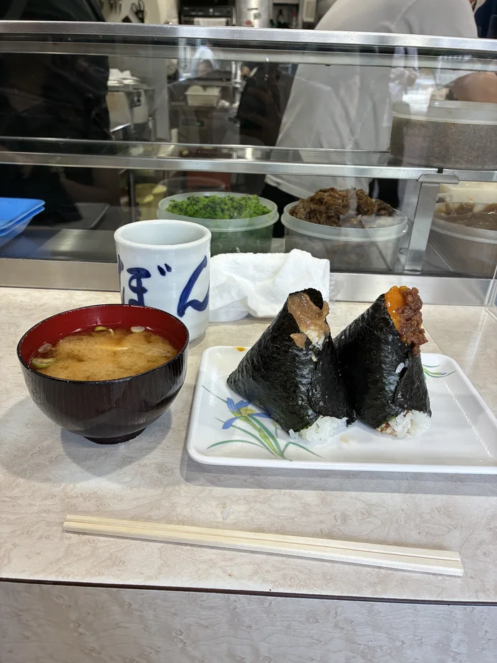 カウンター席に置かれたおにぎり2個とお味噌汁、ぼんごの湯呑み