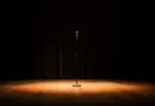 お笑いライブ会場のステージにスポットライトが当たるスタンドマイクのイメージ