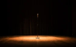 お笑いライブ会場のステージにスポットライトが当たるスタンドマイクのイメージ