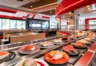 回転寿司店内のレーンに並ぶ寿司皿と赤いアクセントの装飾