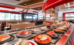 回転寿司店内のレーンに並ぶ寿司皿と赤いアクセントの装飾