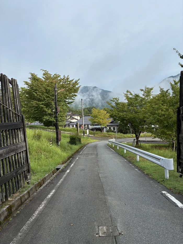 画像 麓へ続く道と、雲がかかった山並み