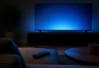 暗い部屋でテレビ画面の光がソファとテーブルを照らしている様子