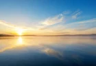 朝日が差し込む湖畔の静かな風景のイメージ