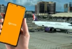 マカオ国際空港の駐機場を背景に、トリファのアプリを起動したスマートフォンを手に持っている様子