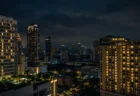 東南アジアの都市の夜景、高層ホテルの窓明かりが立ち並ぶ緊迫感のある情景