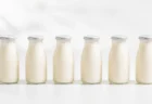 白背景に整列した乳酸菌飲料風の小瓶6本を写した清潔感のある写実的な情景