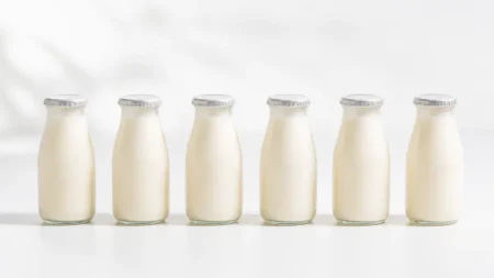 白背景に整列した乳酸菌飲料風の小瓶6本を写した清潔感のある写実的な情景