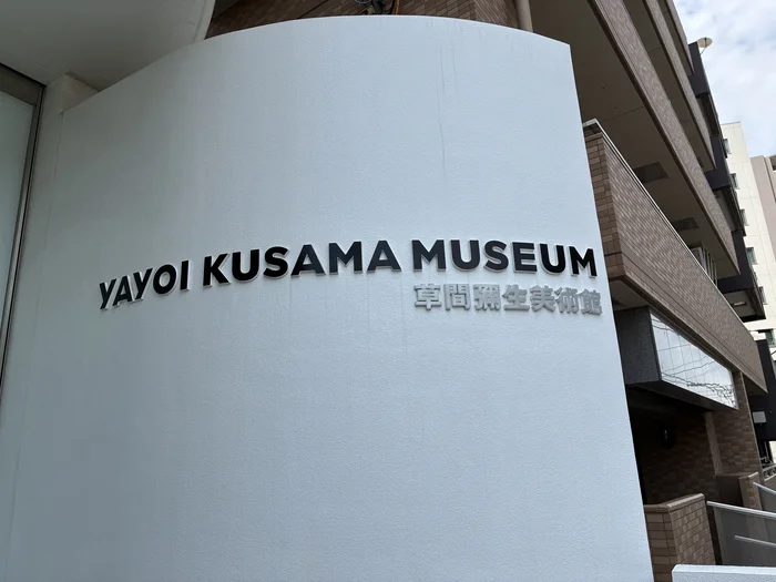 草間彌生美術館の外観と、YAYOI KUSAMA MUSEUMと書かれた壁面のサイン