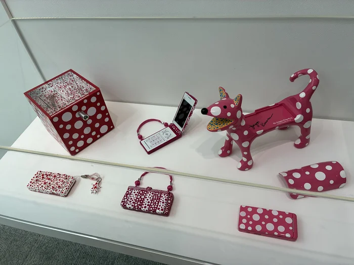 水玉模様の携帯電話やバッグ、犬の置物が並ぶ展示ケース