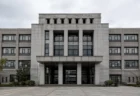 曇り空の下に立つ、市役所を思わせる重厚な官公庁建物の外観