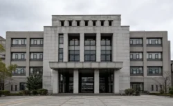 曇り空の下に立つ、市役所を思わせる重厚な官公庁建物の外観