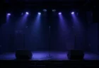 小さなライブハウスの無人ステージと青紫のスポットライト