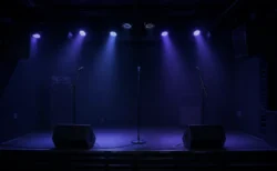小さなライブハウスの無人ステージと青紫のスポットライト