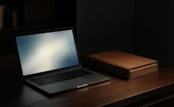 暗い部屋でノートPCの画面が発する柔らかな光と書類ファイル