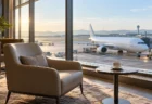 朝の空港の窓越しに見える駐機中の旅客機と無人のラウンジの椅子