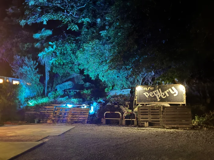 夜の駐車場の奥にライトアップされた cafe perypery の看板