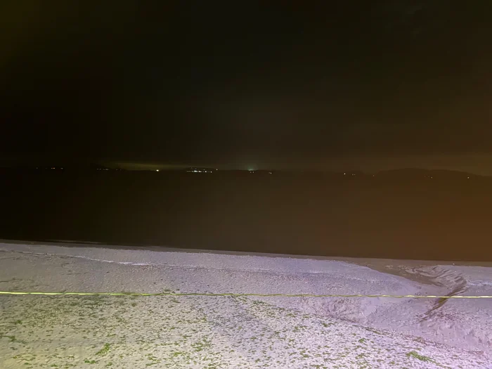 夜の浜辺と暗い海、対岸に小さく光る街の灯り