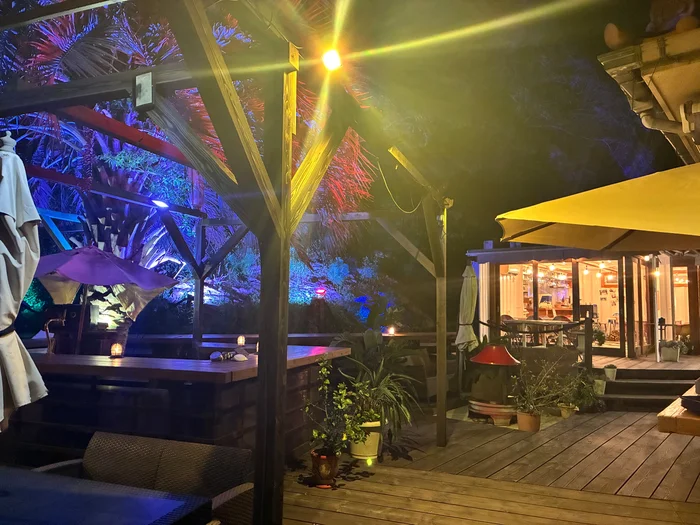 夜のウッドデッキのテラス席と、ガラス越しに明かりが見える店舗