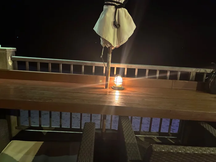 夜の海に面した木のカウンター席とランタンの明かり