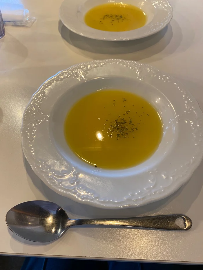 白いスープ皿に入った黄色いスープとハート形の持ち手のスプーン