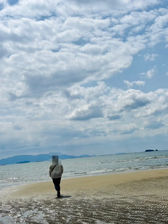 青空と雲の下に広がる遠浅の浜辺と海